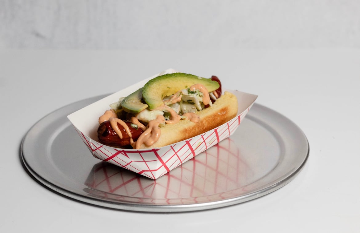 Hot dog topped with avocado