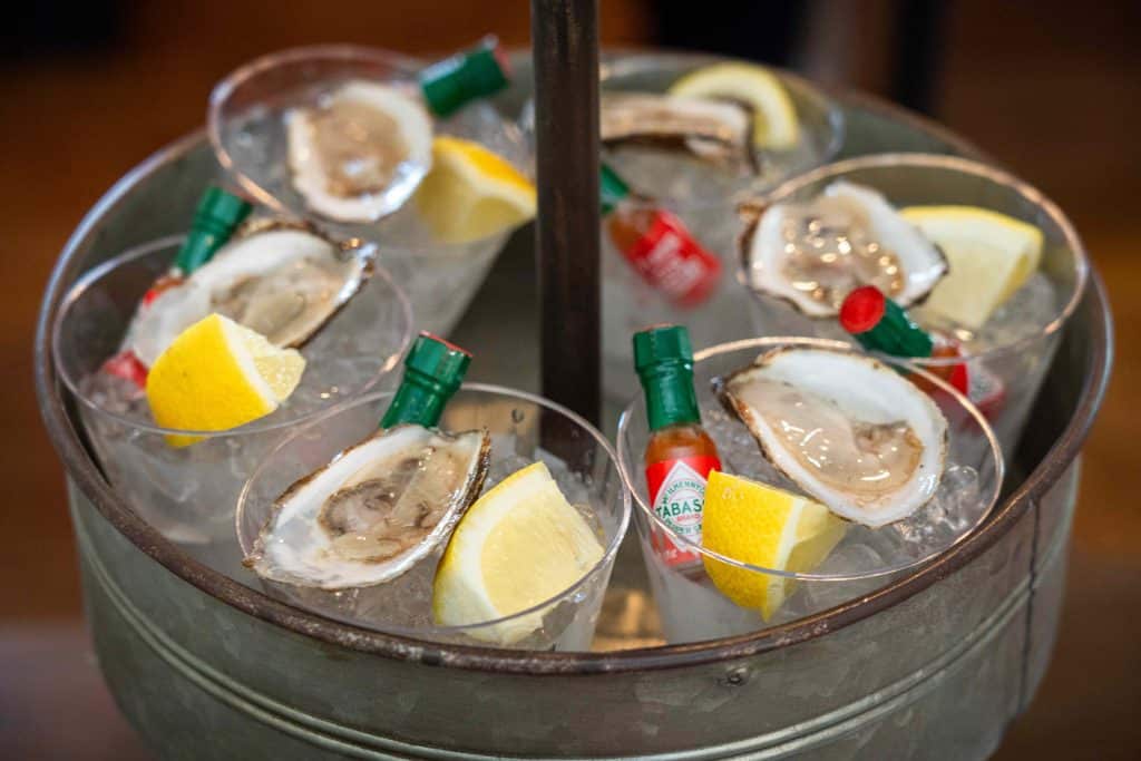 bucket of raw oysters with lemon and Tabasco sauce
