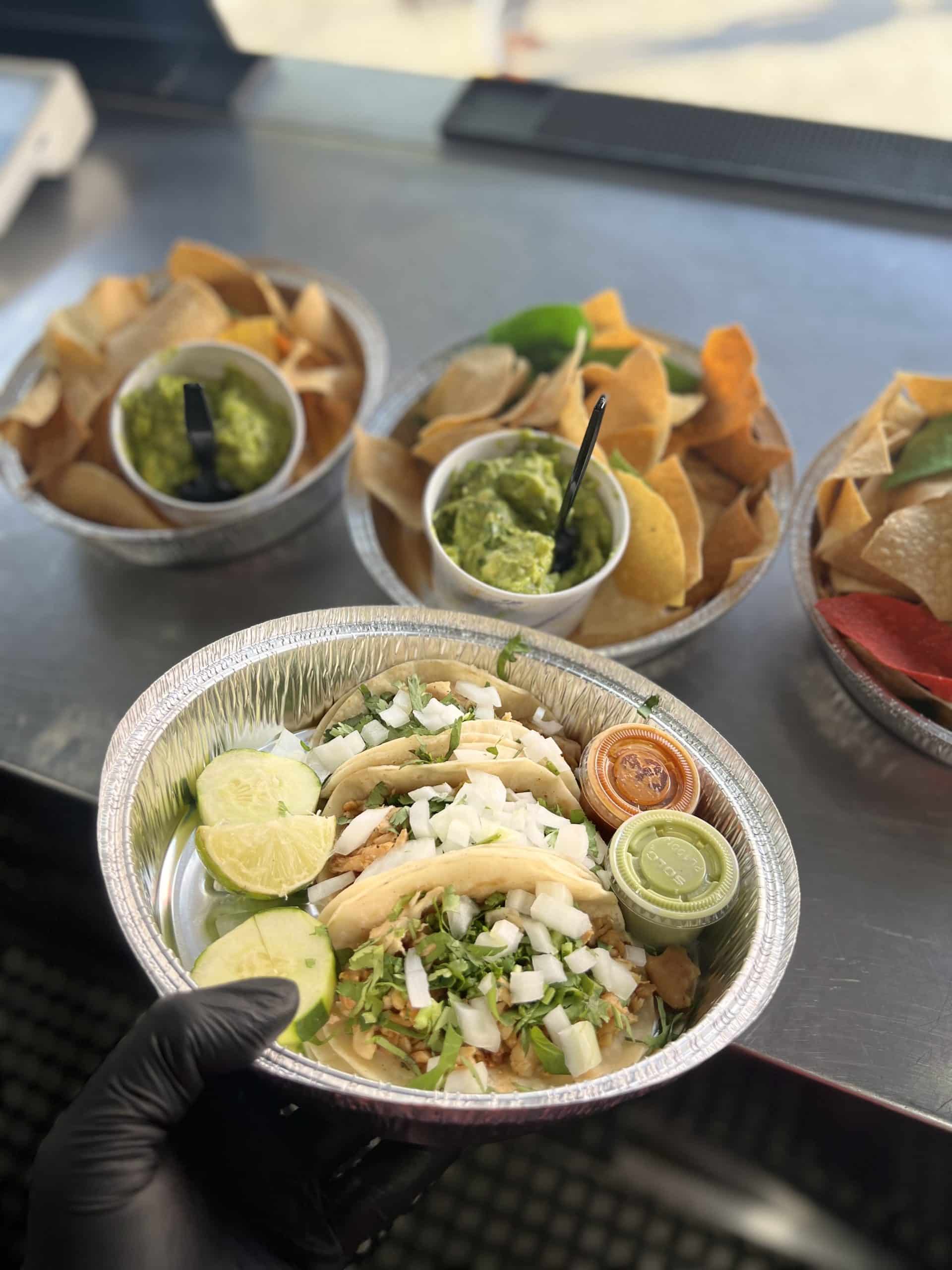 takeout plates of tacos and chips with guacamole
