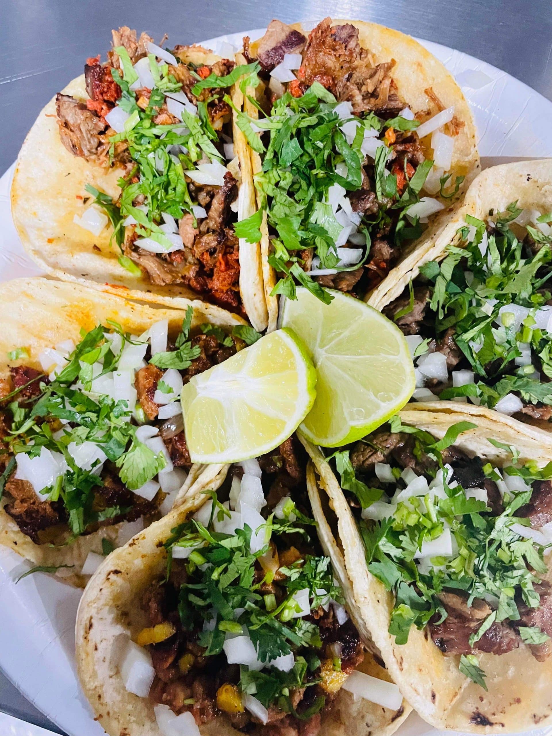 plate of various tacos with lime wedges