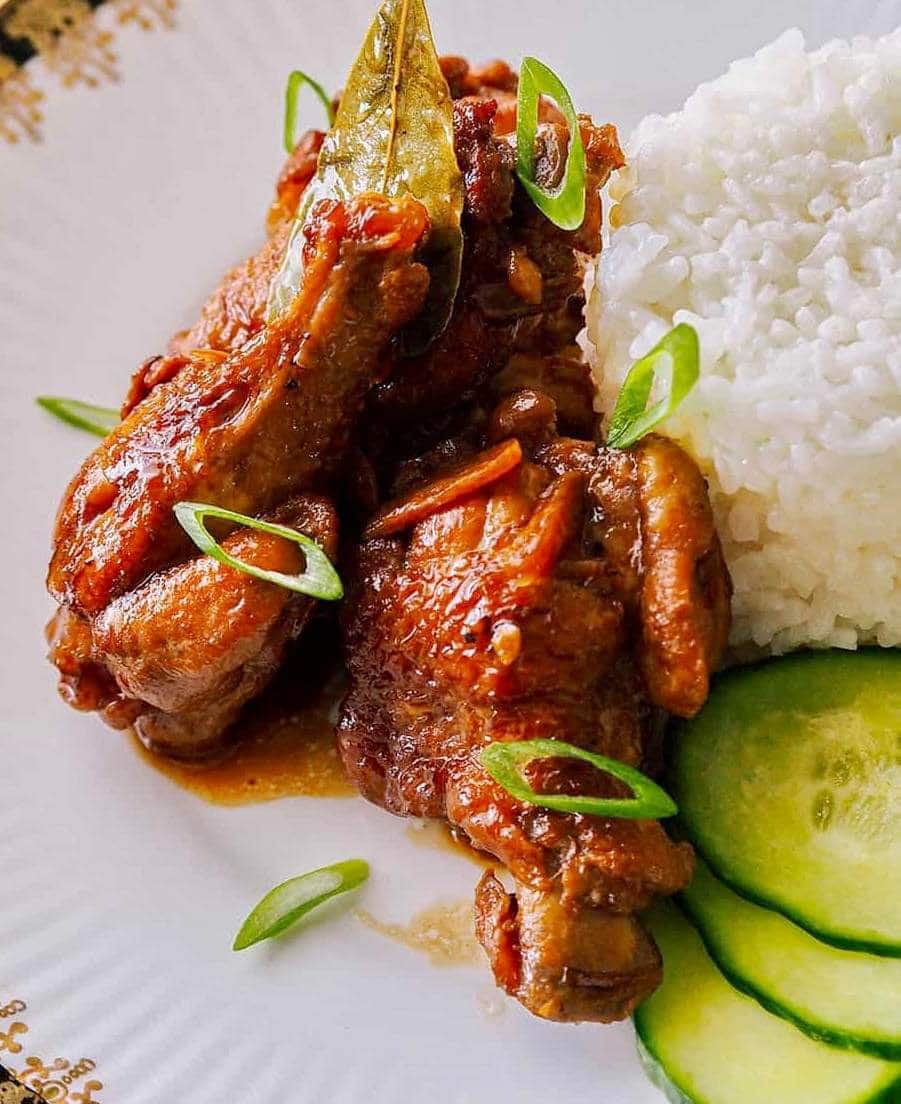 chicken adobo with a side of rice and cucumbers topped with scallions