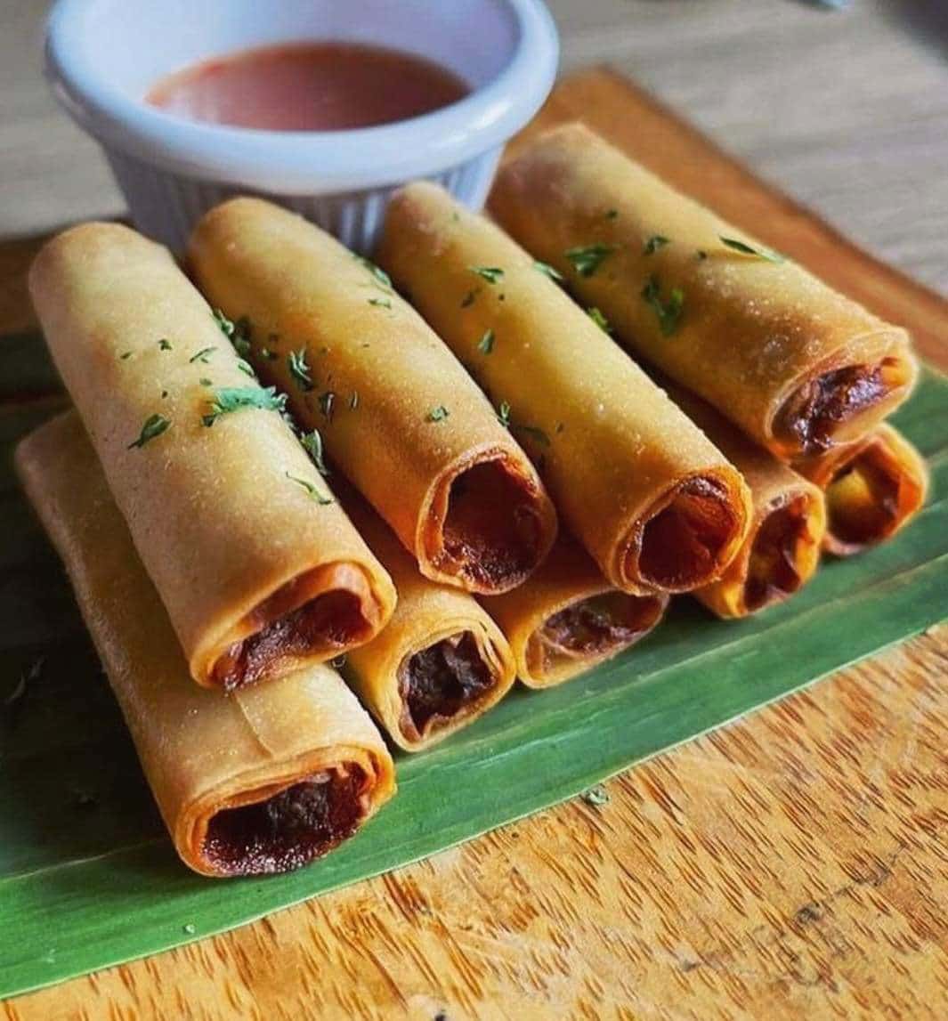 stack of 9 crispy lumpia shanghai with a side of dipping sauce