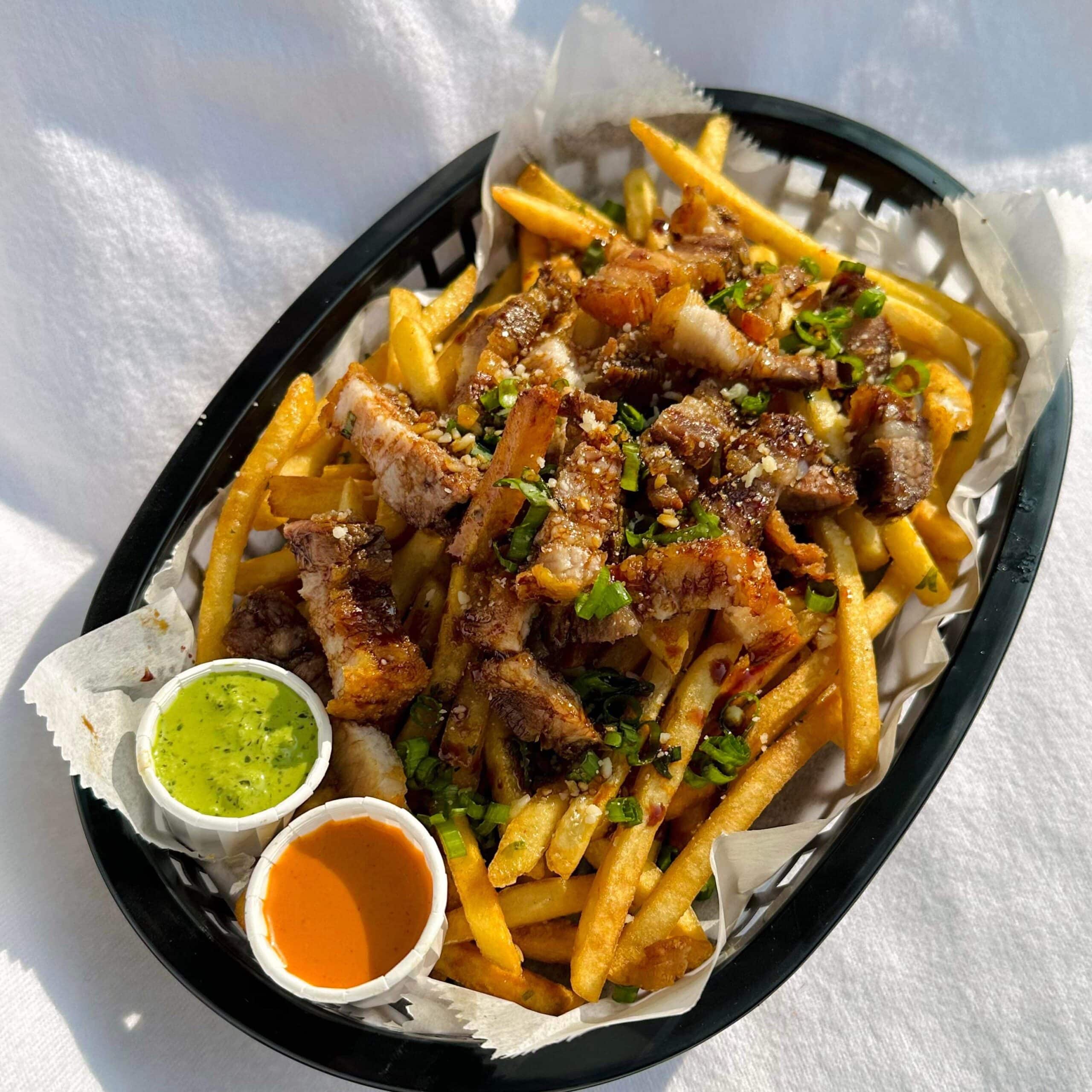plastic basket of loaded french fries with two dipping sauces